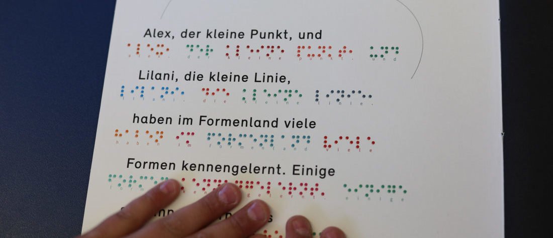 Kinderhände lesen eine Punktschriftgeschichte.