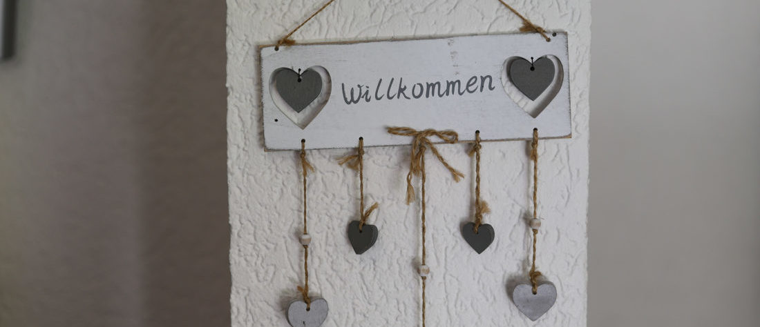 Ein Willkommensschild, verziert mit mehreren Herzen, das eine freundliche und einladende Atmosphäre vermittelt.