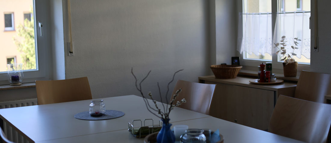 Eine Tischreihe mit vielen Stühlen. Auf dem Tisch sind dekorative Elemente arrangiert, die eine gemütliche Atmosphäre schaffen.