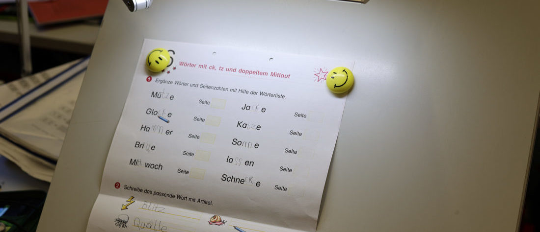 Ein vergrößertes Arbeitsblatt, das an einem hochgestellten Schreibtisch angeheftet ist. Das Blatt wird von einer Arbeitsleuchte beleuchtet, um eine klare Sicht zu gewährleisten und das Arbeiten zu erleichtern.