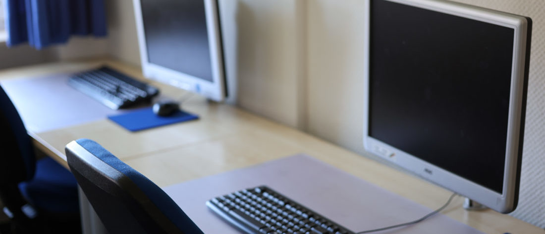 Zwei Computer-Arbeitsplätze, jeweils ausgestattet mit einem Schreibtischund einem Monitor. Die Arbeitsplätze sind ordentlich und funktional eingerichtet.