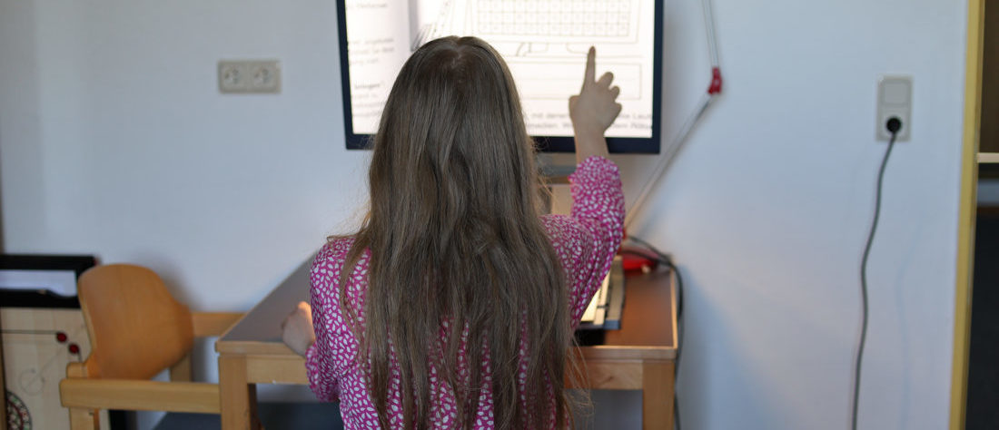 Eine Schülerin arbeitet an einem Lesegerät, das ihr hilft, Texte auf einem Monitor vergrößert anzuzeigen. Das Gerät unterstützt sie dabei, besser lesen zu können.