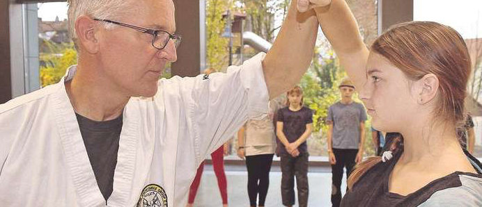 Thomas Weltin zeigt einer Schülerin, wie man sich mit den Armen verteidigt.