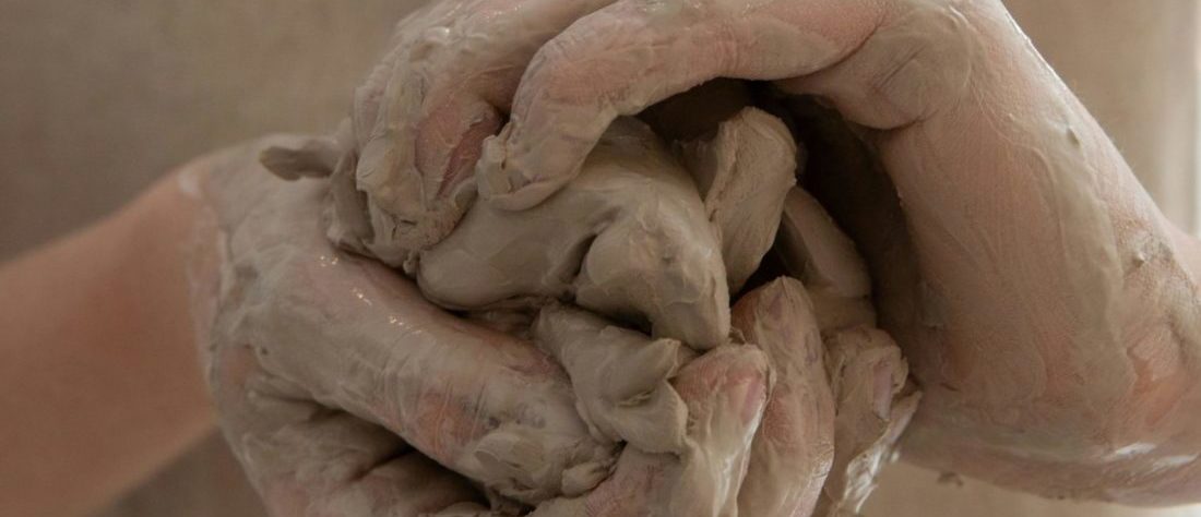 Hände halten Ton und arbeiten damit.