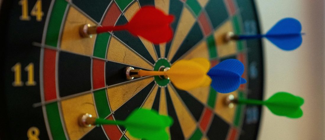 Eine Dartscheibe mit bunten Pfeilen ist zu sehen.