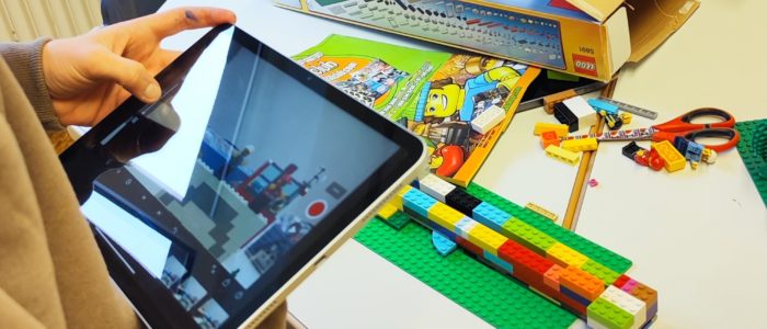 Lego Creator Aufnahmen Ein Kind mit einem Tablet in der Hand, welches Aufnahmen von gebautem Lego macht.