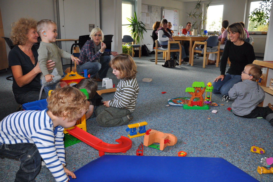 Kinder und Erwachsene, die in einem großem Raum miteinander spielen