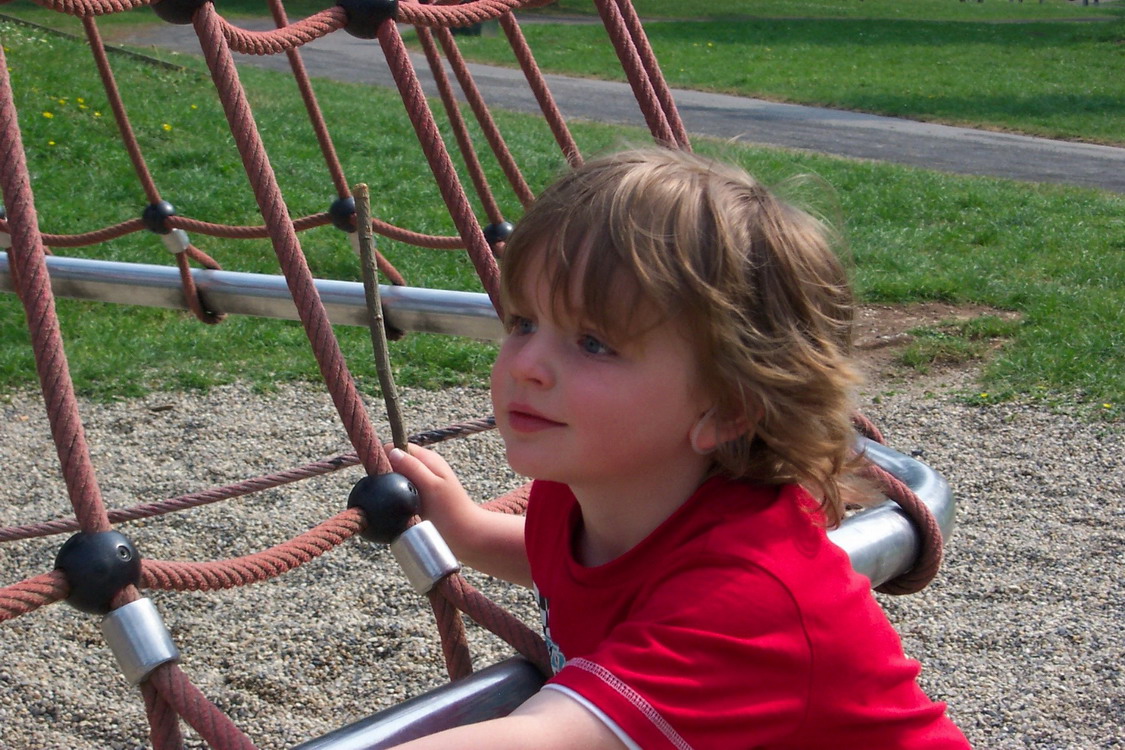 Ein Kind klettern an einem Tauspielgerät.