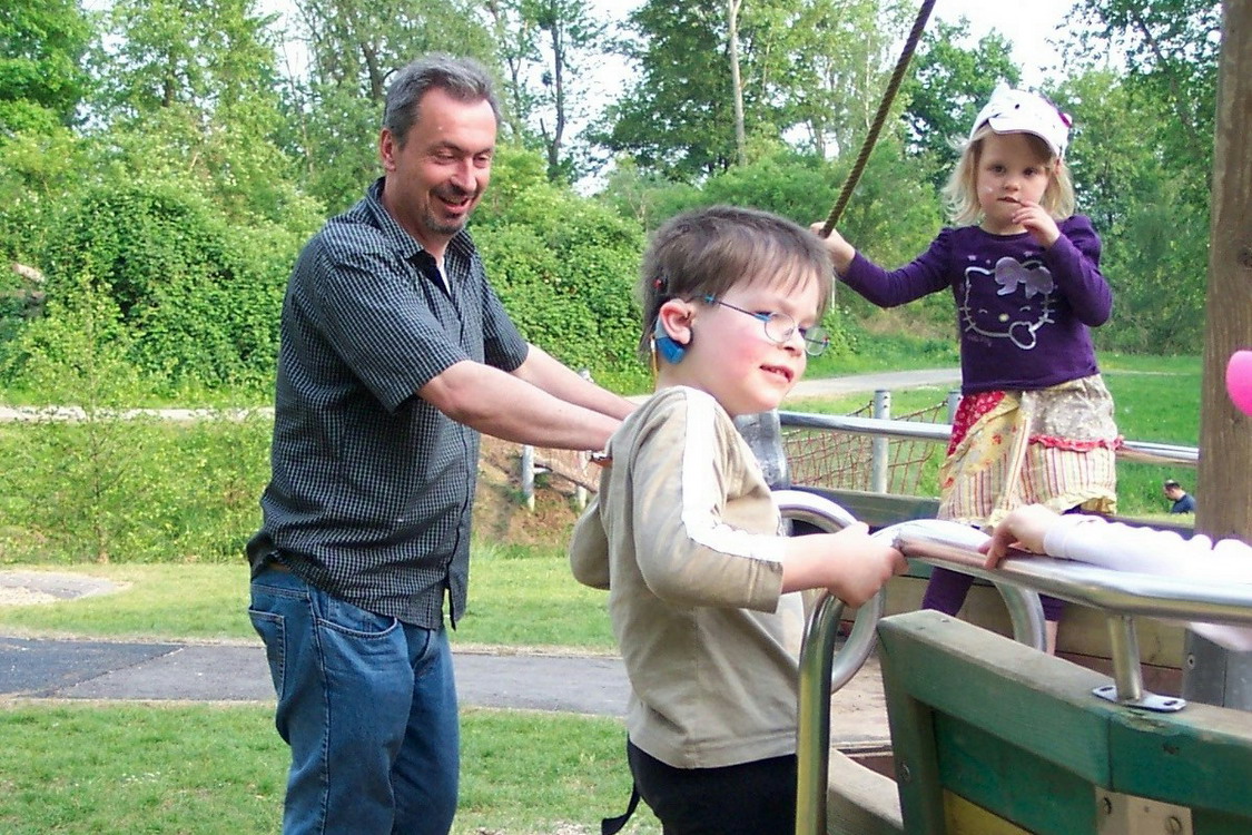 Ein Erwachsener und zwei Kinder spielen an einem Spielgerät