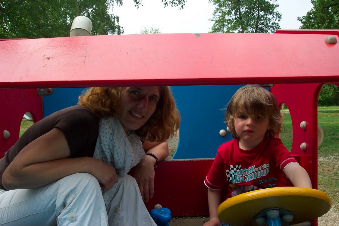 Erwachsene und Kind schauen aus einem Spielgerät raus.