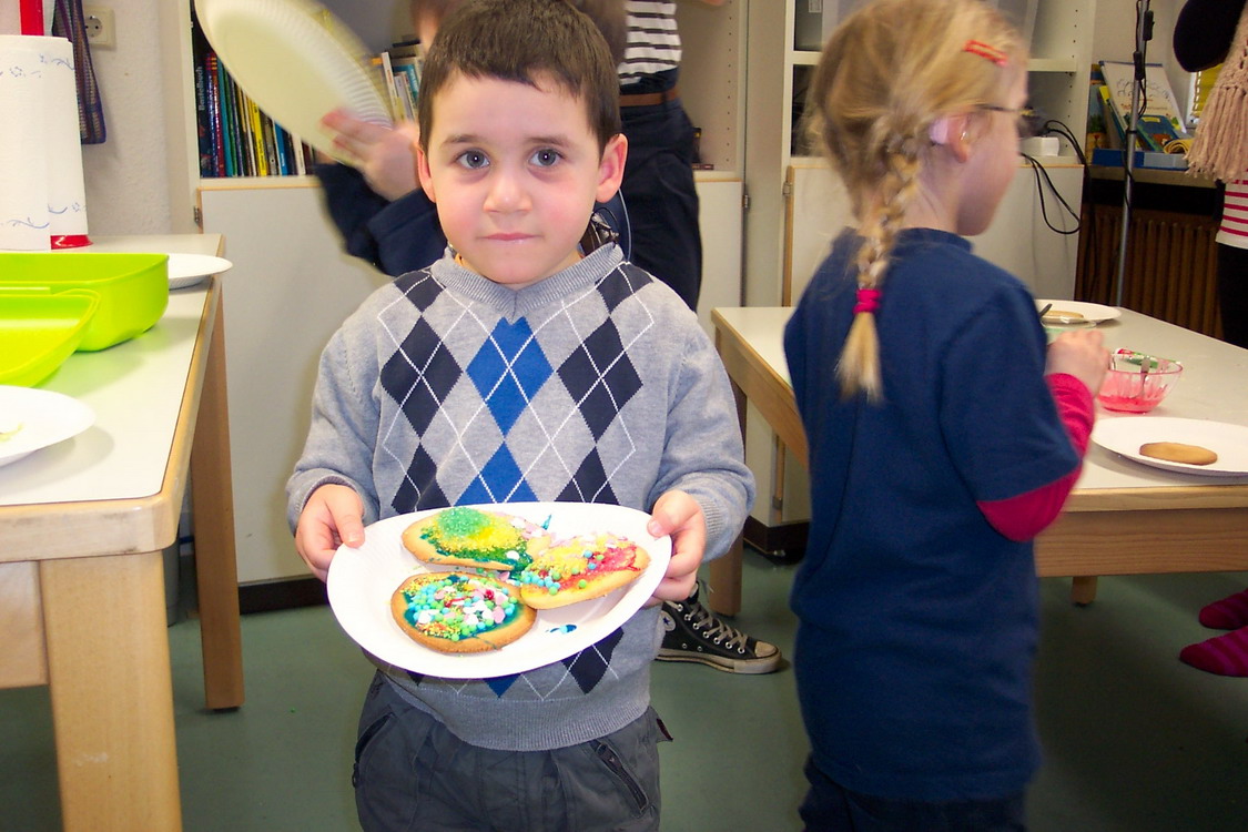 Ein Kind mit einem Teller mit gebackenen Kuchen.