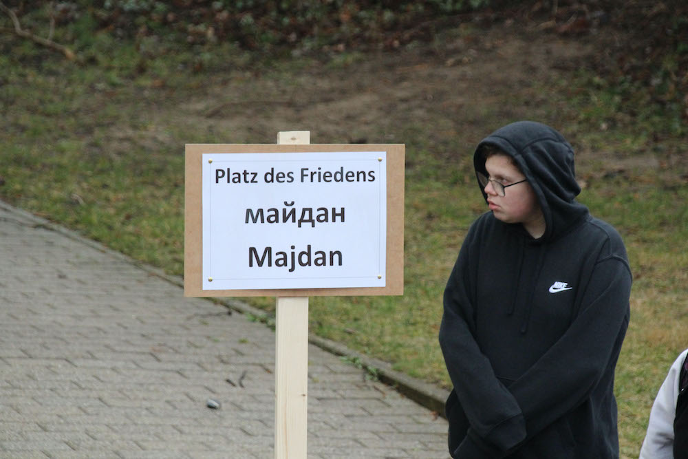 Ein Schild in drei Sprachen Platz des Friedens