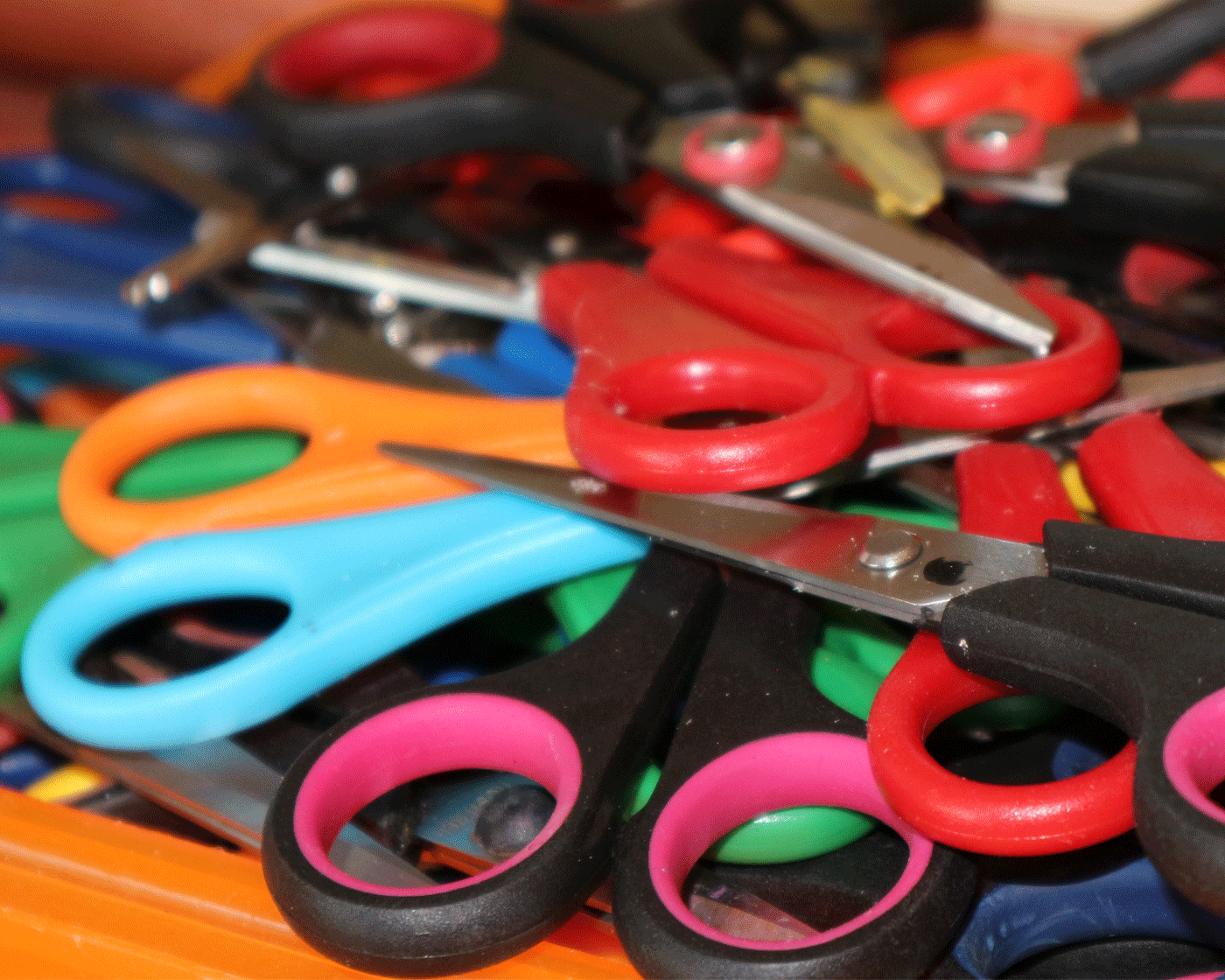 Viele bunte Scheren liegen auf einem Tisch.
