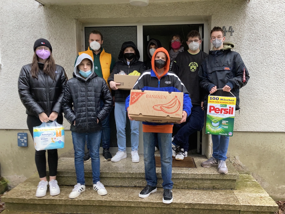 Eine Gruppe von Schülerinnen und Schülern, die Kartons halten.