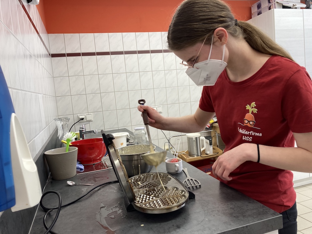 Eine Schülerin backt Waffeln.